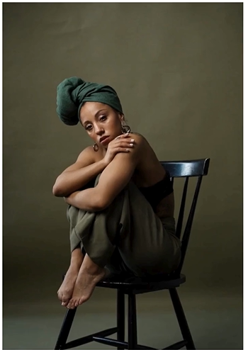 A woman sits on a chair, lost in deep contemplation.