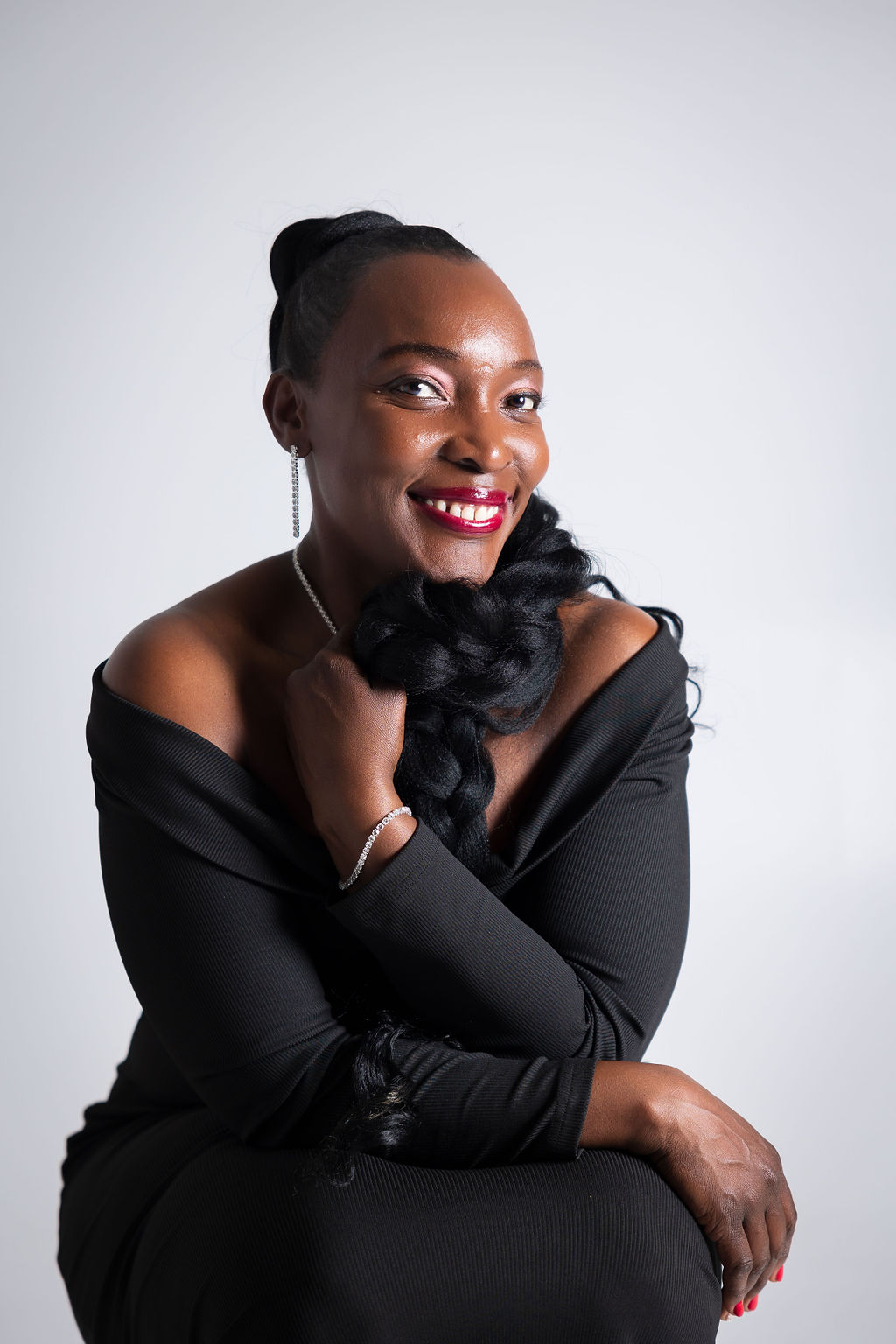A stunning black woman donning a black dress and red lipstick.